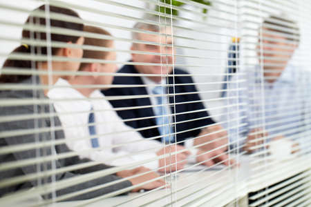 Business team sitting behind blindsの写真素材