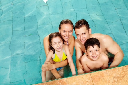 Photo of happy family in swimming pool smiling at camera の写真素材