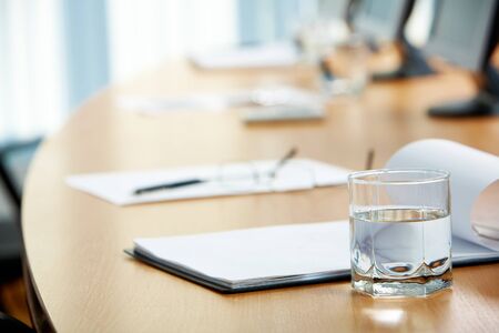 Image of workplace with paper, glass of water and monitors near byの写真素材