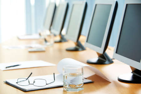 Image of workplace with paper, glass of water, eyeglasses and monitors near byの写真素材