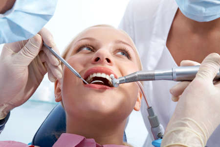 Image of young woman during inspection of oral cavity by dentist and assistantの写真素材