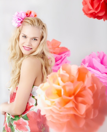 Happy woman with pink flower in wavy hair looking at cameraの写真素材