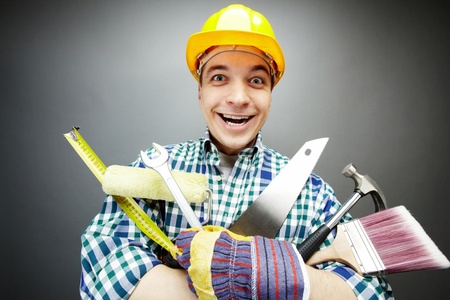 Portrait of happy craftsman with different tools in handsの写真素材