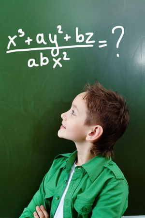 Portrait of smart lad looking at blackboard with algebraic formula on itの写真素材