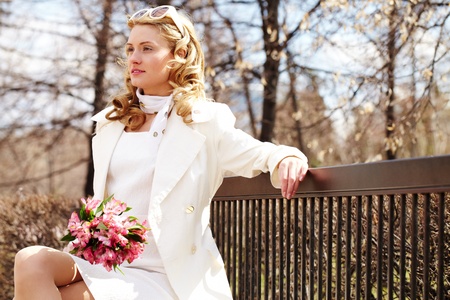 A pretty woman with flowers sitting on bench in park の写真素材