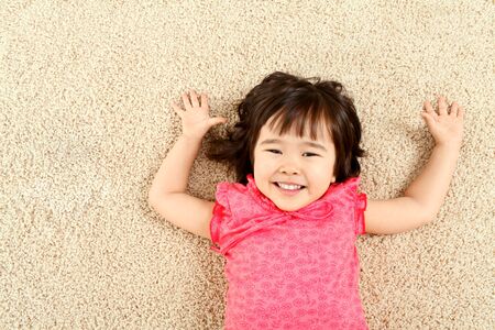 Portrait of cute child laughing while lying on rugの写真素材