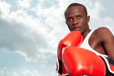 Image of a boxer in red gloves against cloudy skyの写真素材