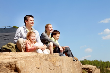 Portrait of family of travelers sitting on rocky cliffの写真素材
