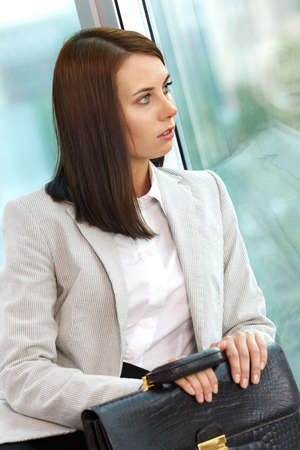 Portrait of smiling businesswoman with briefcase looking through windowの写真素材