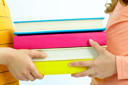Close-up of childish hand giving books to classmateの写真素材