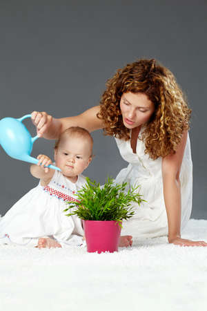 Portrait of pretty woman and her daughter watering green plantの写真素材