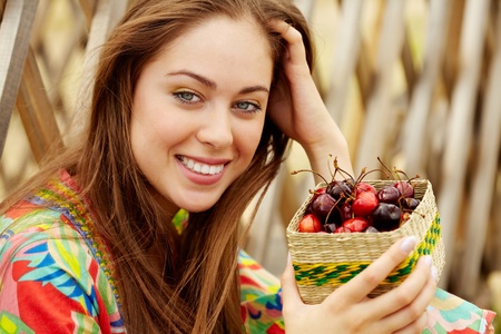 Portrait of pretty girl holding cherries and looking at camera