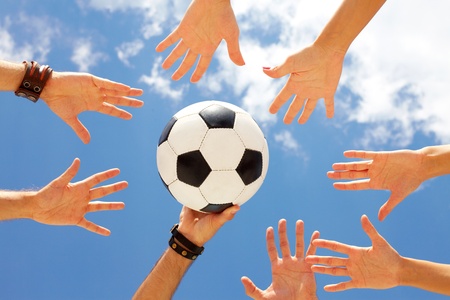 A football ball in circle of hands 