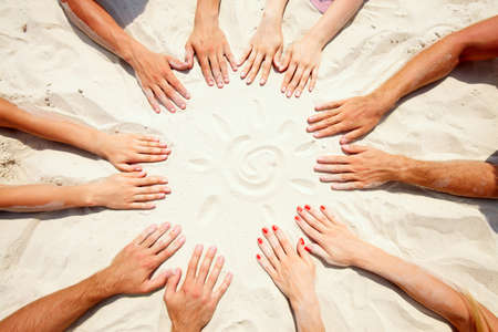 Circle of hands on sand with a sun の写真素材