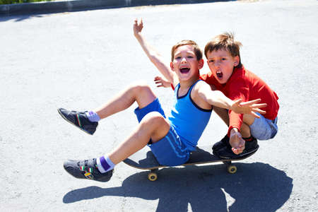 Two cheerful boys sitting on skateboardの写真素材