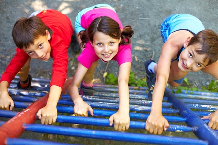 Three little children climbing ladder and looking at cameraの写真素材