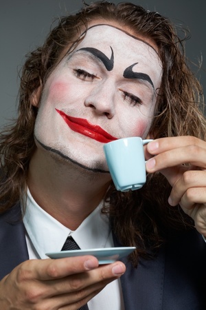 Portrait of businessman with painted face drinking coffee の写真素材