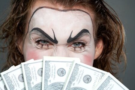 Painted face behind several banknotes の写真素材