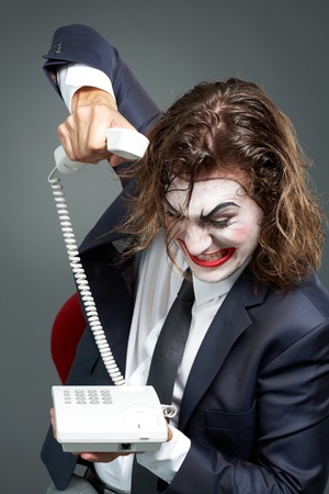 Portrait of furious businessman with theatrical makeup ringing offの写真素材