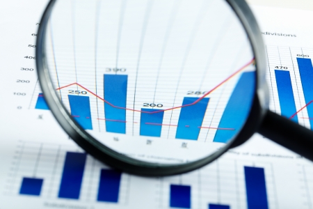 Close-up of magnifying glass over business document at workplace 