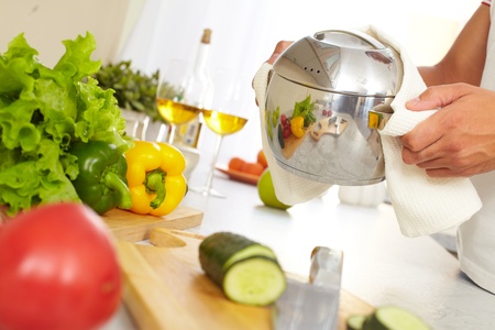 Image of pan in human hands with reflection of fresh vegetables and knife on wooden boardの写真素材