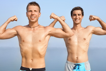 Two happy guys showing their musclesの写真素材