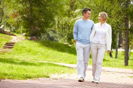 Portrait of young amorous couple walking in park in summer Portrait of young amorous couple walking in park in summer