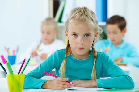 Portrait of lovely girl drawing with classmates on backgroundの写真素材