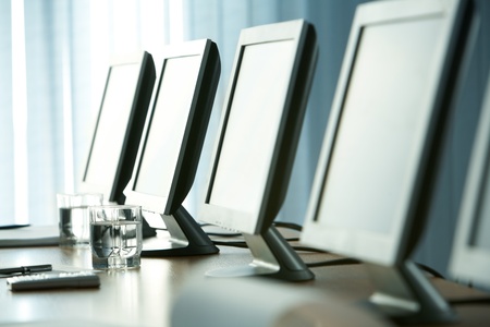 Close-up of workplace with glass of water, some objects and monitors on itの写真素材