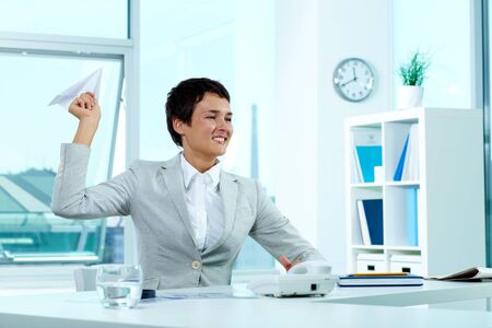 Portrait of a successful employer at workplace holding paper planeの写真素材