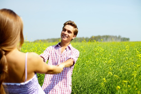 Portrait of happy guy looking at his girlfriend in flower fieldの写真素材