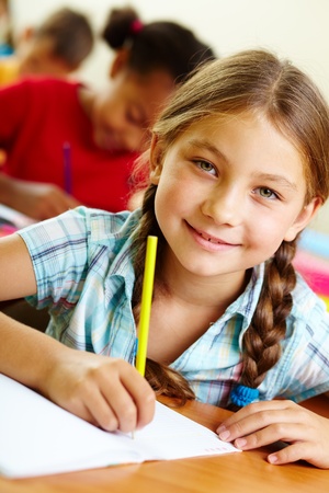 Portrait of lovely girl drawing in copybook at lessonの写真素材