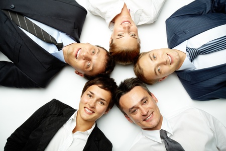 Five business people lying in floor, looking at camera and smilingの写真素材