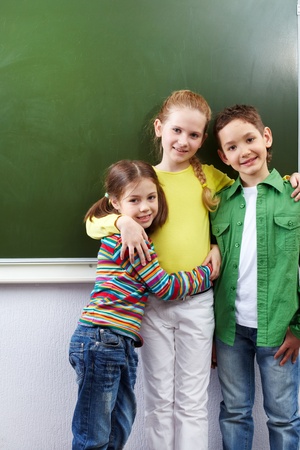 Group of happy classmates looking at camera by whiteboardの写真素材