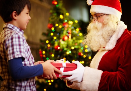 Photo of happy boy taking gift from Santa Claus handsの写真素材