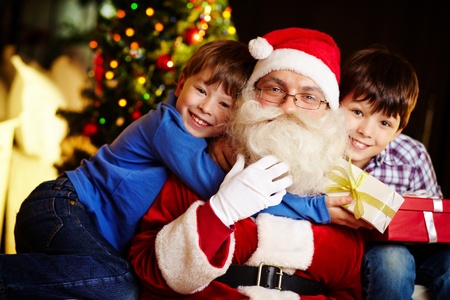 Photo of happy boy embracing Santa Claus with cute kid near byの写真素材