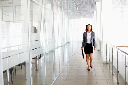 Businesswoman walking along the office corridorの写真素材