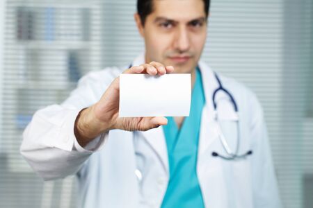 Male doctor showing visiting card and looking at cameraの写真素材
