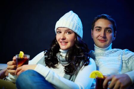 Portrait of happy couple holding glasses of hot tea and looking at cameraの写真素材