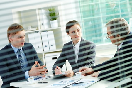 Portrait of three business people sharing ideas at meeting in officeの写真素材