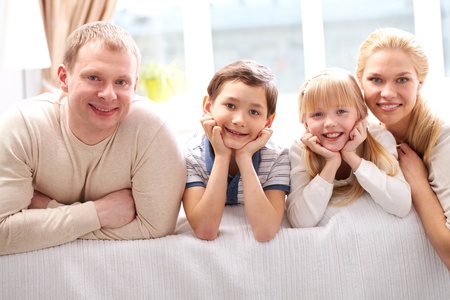 A young family of four looking at camera and smiling