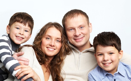 A young family of father, mother and two kids looking at camera and smilingの写真素材
