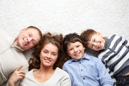 A young family of father, mother and two kids looking at cameraの写真素材