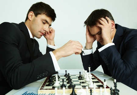 Image of businessman making move while playing chess with his rival in front of himの写真素材
