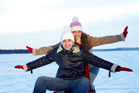 Portrait of happy couple in warm clothes tobogganing in winter の写真素材