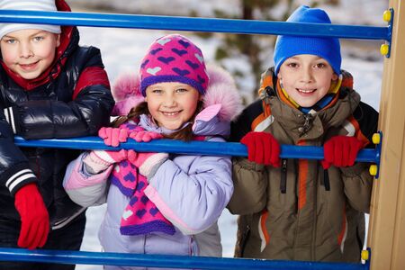 Happy kids in winterwear looking at camera outside