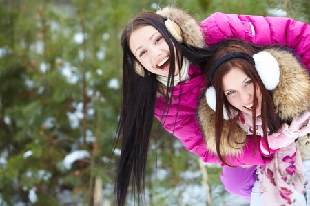 Portrait of two pretty girls in winter park having funの写真素材