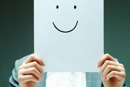 Image of female holding paper with drawn smile by her faceの写真素材