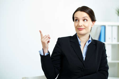 Portrait of happy office worker looking aside while pointing upwardsの写真素材