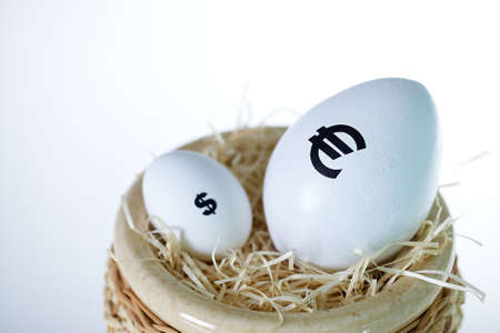 Image of big white egg with euro sign and small egg with dollar sign in nestの写真素材
